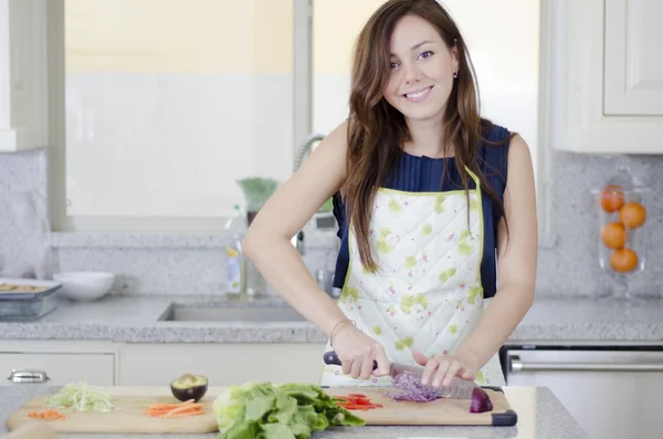 Krásná brunetka v kuchyni řezání zeleniny — Stock fotografie