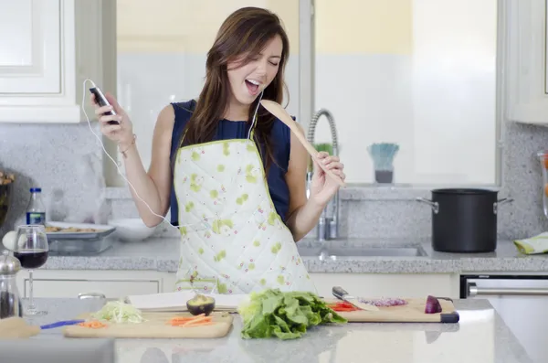 Mooie brunette zingen in de keuken — Stockfoto