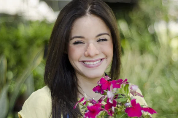 Χαριτωμένο ευτυχισμένος κορίτσι χαμογελά σε έναν κήπο με λουλούδια — Φωτογραφία Αρχείου