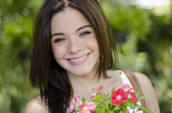 Closeup portrait of cute young girl with flowers smiling in orchard — Stock Photo, Image