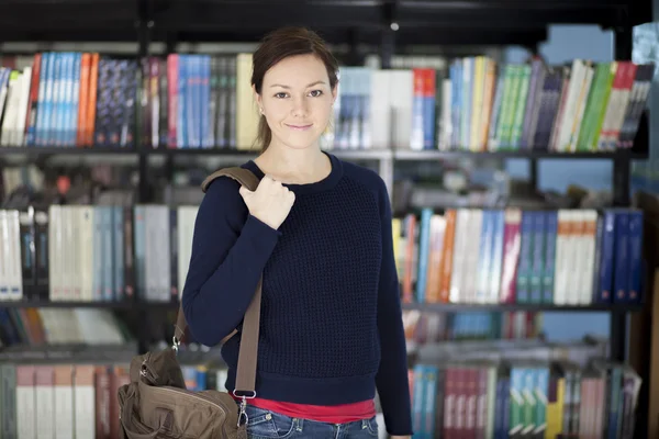 Usměvavá mladá žena v knihovně — Stock fotografie
