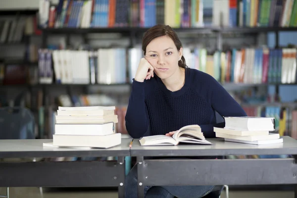 Mujer joven aburrida estudiando en la biblioteca —  Fotos de Stock