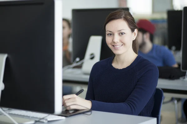 Улыбающаяся молодая женщина работает за компьютером — стоковое фото
