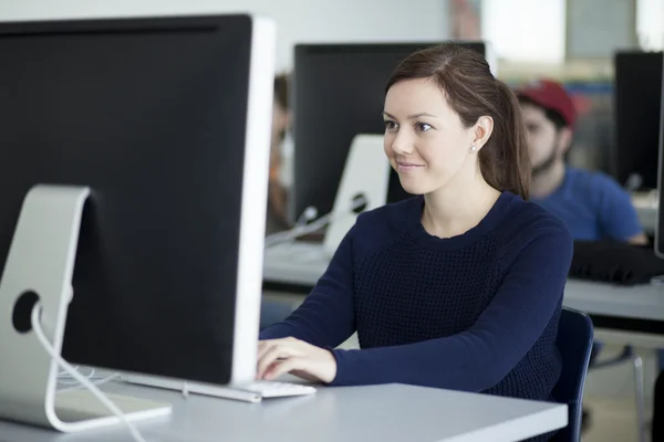 Usměvavá mladá žena, pracující na počítači — Stock fotografie