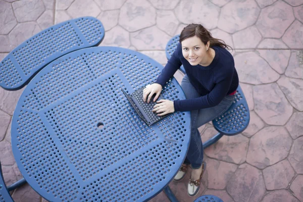 Lachende aantrekkelijke jonge vrouw die werkt op een laptop — Stockfoto