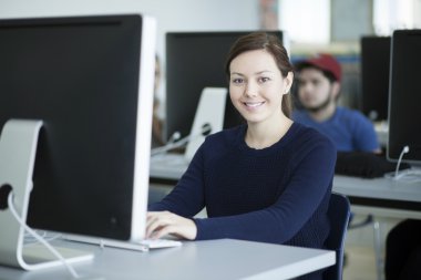 bir bilgisayarda çalışan genç kadın gülümsüyor