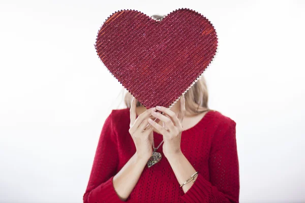 Sevimli genç bir kadın kalp simgesi tutan — Stok fotoğraf