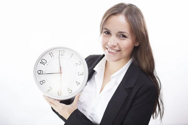 Jolie femme brune souriante tenant une horloge — Photo