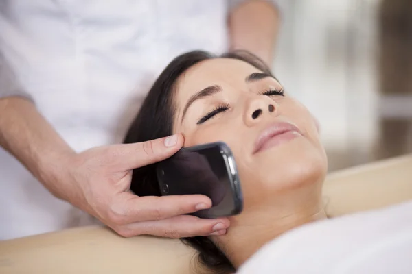 Młoda dama mówiąc na telefon podczas masażu — Zdjęcie stockowe