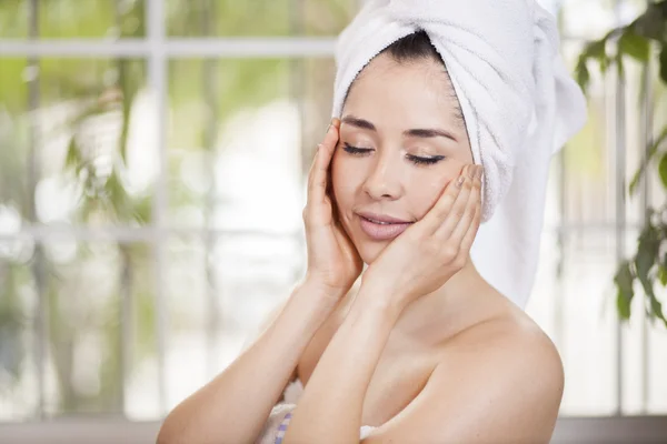 Young lady wrapped in towel, touching her face — Stock Photo, Image