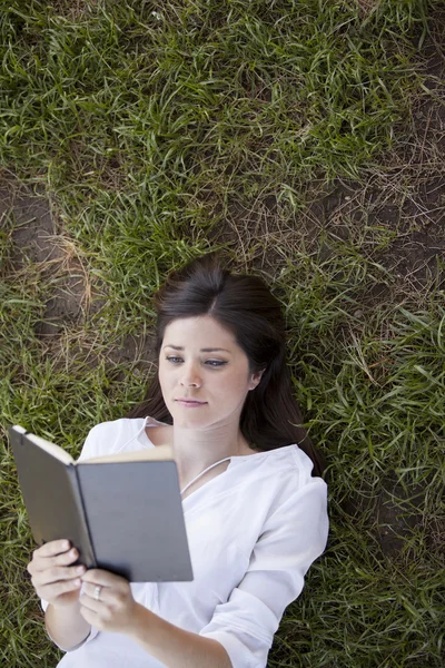 Chica acostada en la hierba y leyendo un libro —  Fotos de Stock