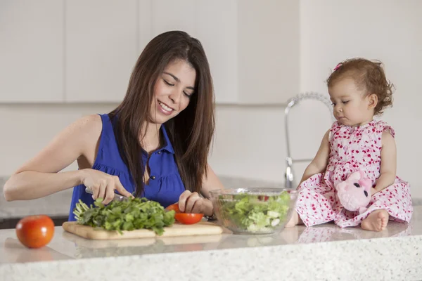 Morena mãe e filha preparam salada na cozinha — Fotografia de Stock