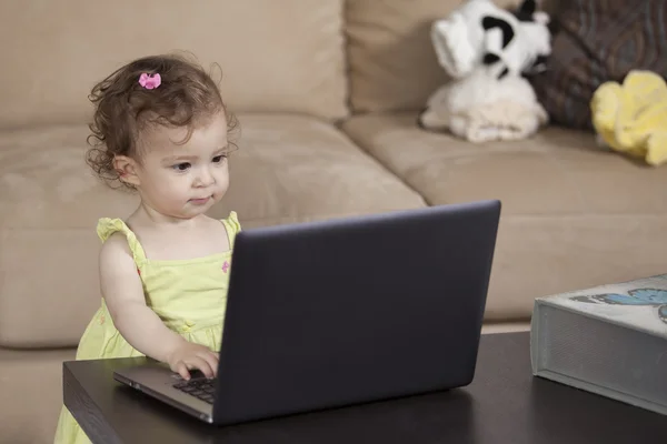 Pequena criança bonita brincando com laptop em casa — Fotografia de Stock