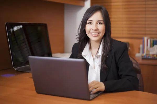 Empresária sentada à mesa no lobby do escritório e usando laptop — Fotografia de Stock