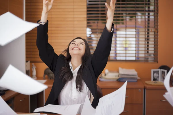 Ung kvinna och flygande papper i office — Stockfoto