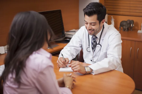 Médico masculino escrevendo algo enquanto o paciente está falando em uma sala — Fotografia de Stock