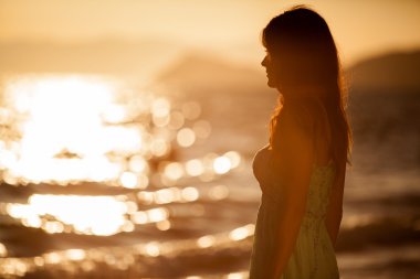 Gün batımında sahilde genç bir kadın.