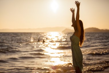 Gün batımında sahilde genç bir kadın.