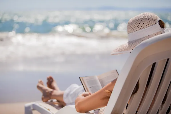 Mulher bonita lendo um livro na praia — Fotografia de Stock