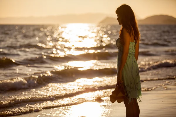 Młoda kobieta na plaży o zachodzie słońca — Zdjęcie stockowe