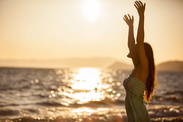 Молода жінка на пляжі на заході сонця — стокове фото