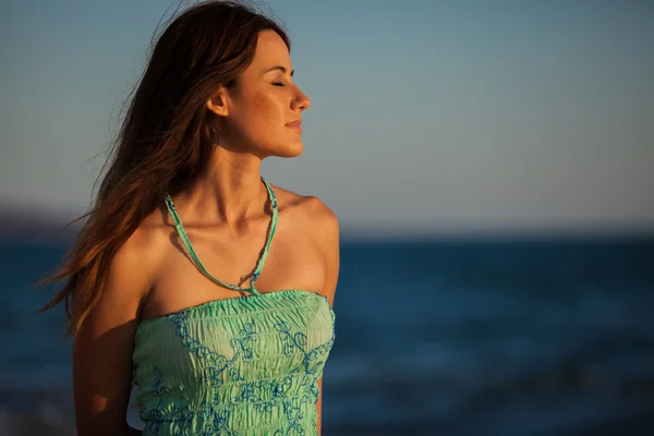 Jovem mulher na praia ao pôr do sol — Fotografia de Stock