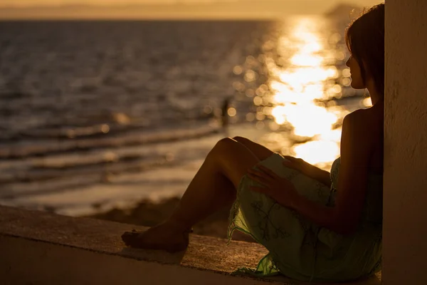 Молода жінка на пляжі на заході сонця — стокове фото