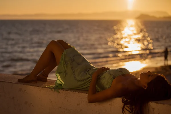 Ung kvinde på stranden ved solnedgang - Stock-foto