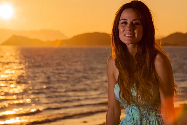 Jonge vrouw op het strand bij zonsondergang — Stockfoto