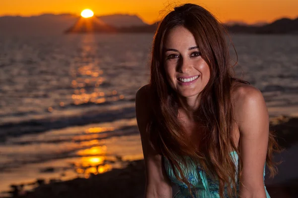 Ung kvinna på stranden vid solnedgången — Stockfoto