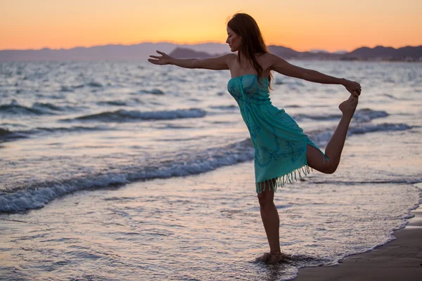 Jeune femme sur la plage au coucher du soleil — Photo