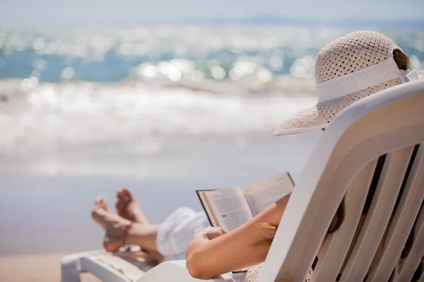 Όμορφη γυναίκα διαβάζοντας ένα βιβλίο στην παραλία Εικόνα Αρχείου