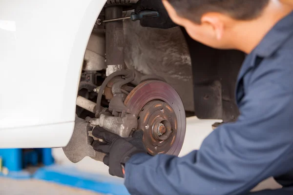 Manliga mekaniker på en bil garage om fastställande av ett hjul — Stockfoto
