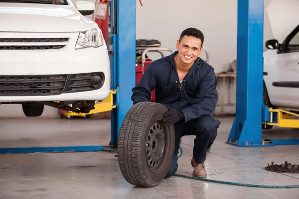 Male mechanic at a car garage fixing a wheel — Stock Photo, Image