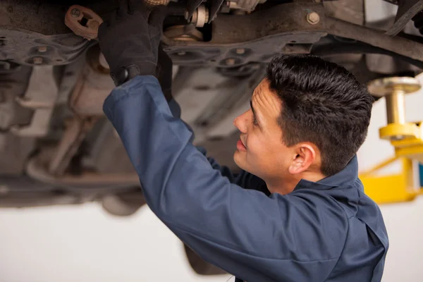 Kfz-Mechaniker untersucht Aufhängung von angehobenem Auto an Reparatur-Tankstelle — Stockfoto
