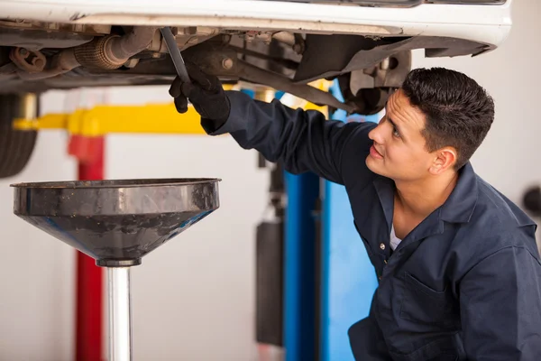 Car mechanic examining car suspension of lifted automobile at repair service station — Stock Photo, Image