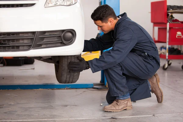 Male mechanic at a car garage fixing a wheel — Stock Photo, Image