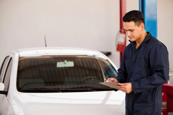 Knappe mechanic schrijven op een Klembord — Stockfoto