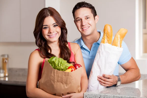 Casal levando mantimentos e pão para a cozinha — Fotografia de Stock