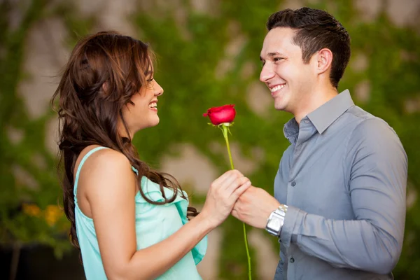 Morena recebendo uma rosa vermelha de seu encontro — Fotografia de Stock