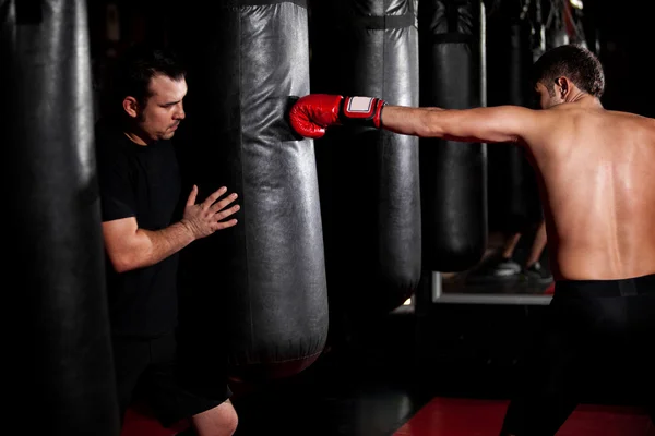 Treinamento de lutador Boxer jovem com saco de soco no ginásio com personal trainer — Fotografia de Stock