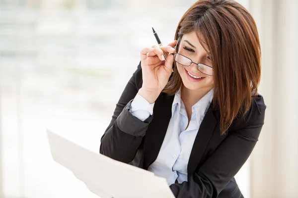 Mulher de negócios bonita ler cuidadosamente os documentos e sorrisos — Fotografia de Stock