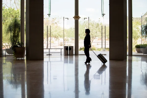 Business woman with luggage standing in the lobby — Stock Photo, Image