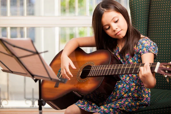 Маленькая девочка играет на гитаре дома — стоковое фото