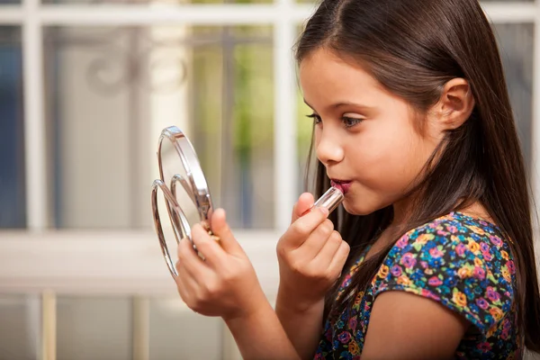 Маленькая девочка пытается покрасить губы — стоковое фото