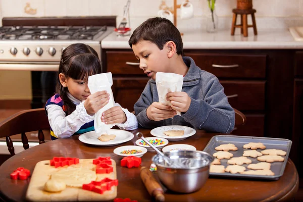 Flickan och hennes bror decorating holiday cookies — Stockfoto