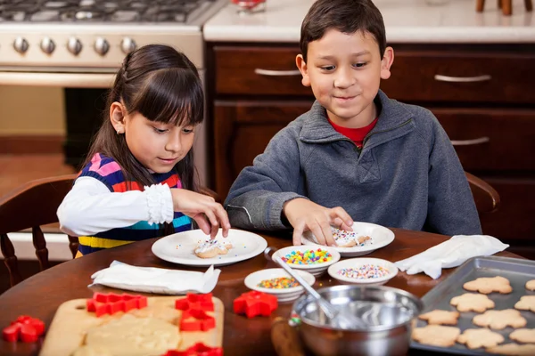 Frères et sœurs qui cuisinent et mangent des biscuits de vacances — Photo