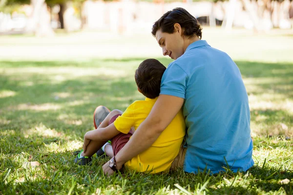 Padre y su hijo están sentados en la hierba —  Fotos de Stock