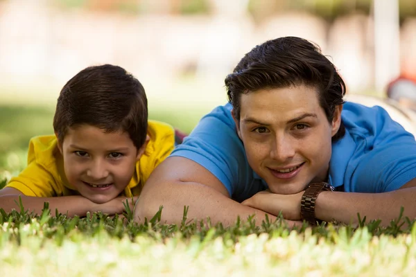 Manden og hans søn ligger på græsset - Stock-foto