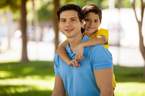 Chico montando cerdito de nuevo en la espalda de su padre — Foto de Stock